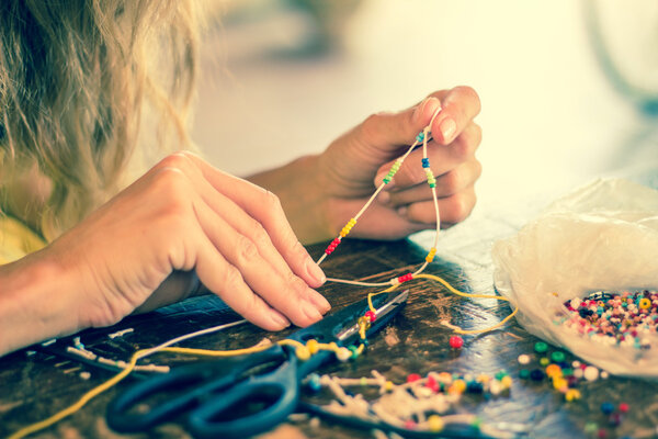 Woman making bracelet at home