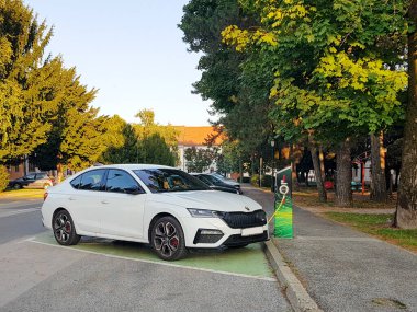 Beyaz Skoda, elektrikli araba şarj oluyor.