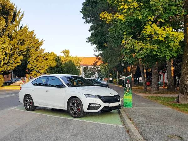 Beyaz Skoda, elektrikli araba şarj oluyor.