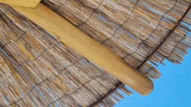 Straw beach umbrella from down side. Made of straw, wood and iron rings.