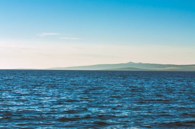 Güzel sahil, mavi deniz ve uzak dağlar. Güneşli bir günde mavi Adriyatik Denizi manzarası.