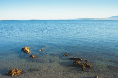 Güzel sahil, mavi deniz ve uzak dağlar. Güneşli bir günde mavi Adriyatik Denizi manzarası.