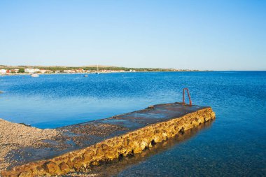 Hırvatistan 'ın Vir kentindeki eski taş köstebek ve mavi deniz. Güneşli bir günde mavi Adriyatik Denizi manzarası.