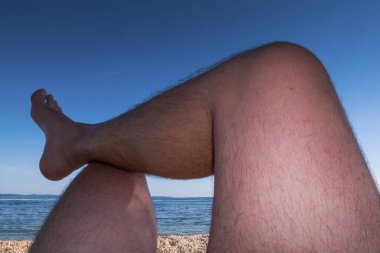 Adamın bacakları kumsalda güneşleniyor. Bakış açısı.