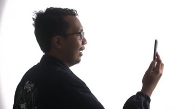 Gözlüklü genç bir adamın akıllı telefonuyla video görüşmesi yaptığı yüksek anahtarlı bir video.