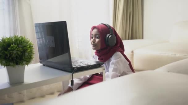 Kırmızı Başörtüsü Takan Asyalı Küçük Bir Kız Bilgisayar Kulaklık Kullanarak — Stok video