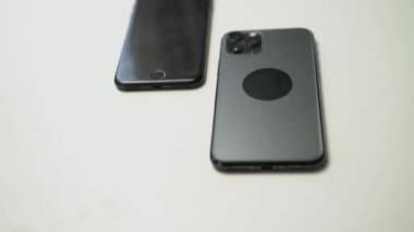 Beyaz masadaki iki siyah akıllı telefonun videosunu kapat.