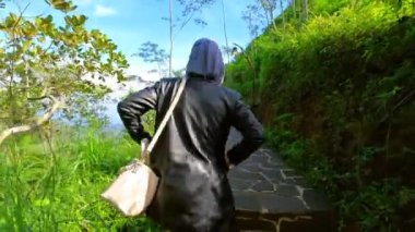 Gökyüzü açık yeşil yüksek bir tepenin kenarında yürüyorum.