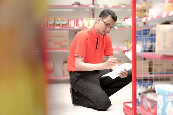  Bir süpermarketin çalışanı üniforma giyer ve envanter raporları için malları kontrol eder..