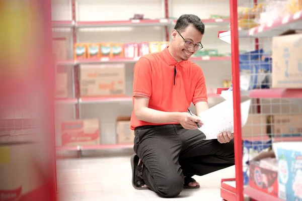 Seorang Karyawan Supermarket Mengenakan Rak Rak Stok Yang Seragam Dengan Stok Gambar Bebas Royalti