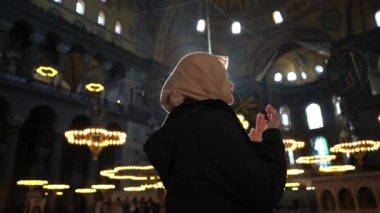 Eşarplı Asyalı Müslüman kadın Hagia Sopia Camii 'nde ellerini kaldırarak dua ediyor.