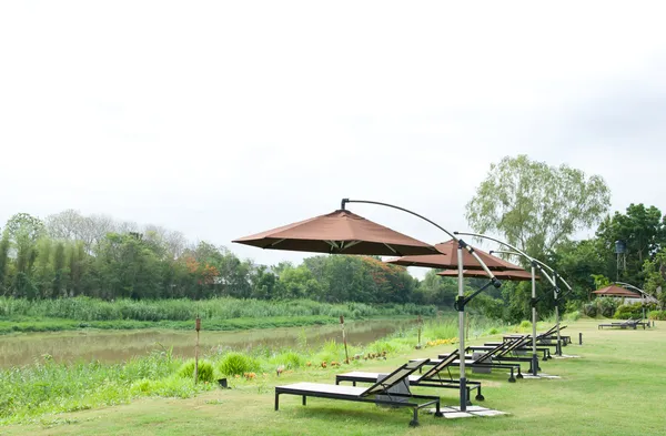 Le parapluie et le siège dans le jardin — Photo