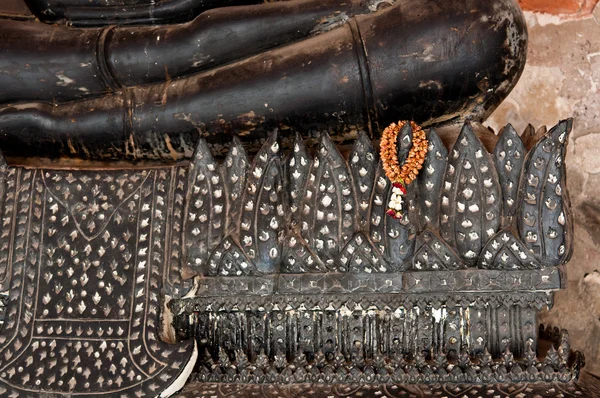 Die getrocknete Girlande hängt an der Basis des schwarzen sitzenden Buddha-Stute — Stockfoto