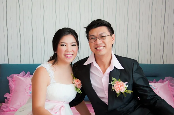 Noiva e noivo sentar-se na cama rosa sorrindo para a câmera Imagens Royalty-Free