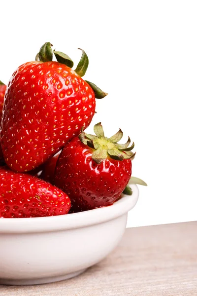 Fresas en plato blanco en el tablero de madera . — Foto de Stock