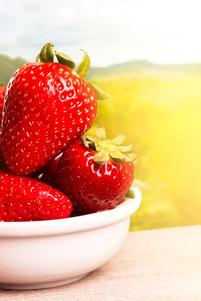 Fraises en assiette blanche sur table en bois . — Photo