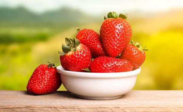 Erdbeeren in weißem Teller auf Holztisch — Stockfoto