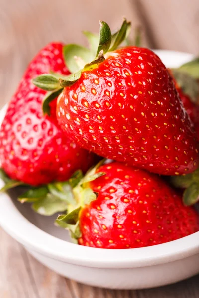 Primer plano de fresas en plato blanco sobre mesa de madera . —  Fotos de Stock