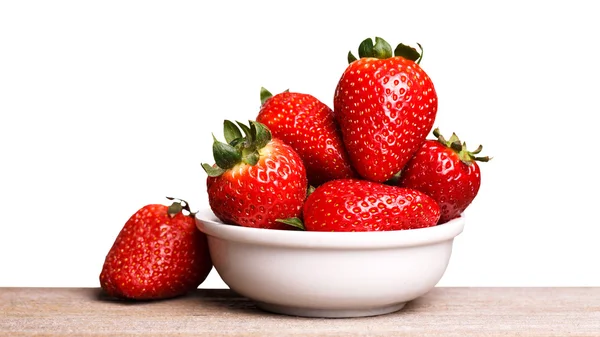 Fresas en plato blanco en el tablero de madera . — Foto de Stock