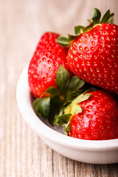 Aardbeien in witte plaat op houten tafel. — Stockfoto