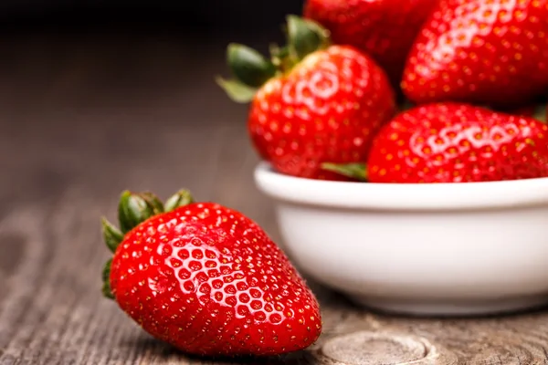 Erdbeeren im weißen Teller auf dem alten Holztisch. — Stockfoto