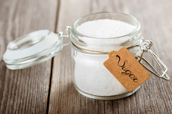 Opened glass jar with sugar.