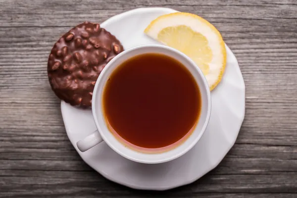 Xícara quente de chá em caneca branca com limão e biscoito de chocolate . — Fotografia de Stock