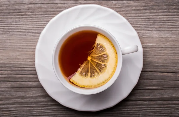 sıcak ahşap masa üzerinde duran limon ile çay fincan.