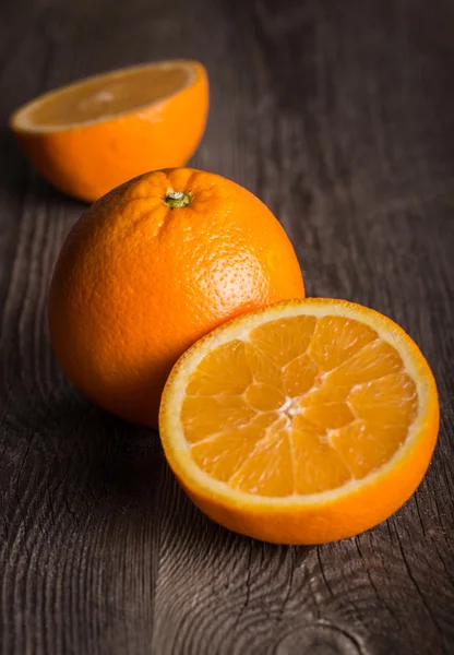 Primer plano de la fruta naranja en la vieja mesa de madera. Enfocado en la parte superior de la naranja media —  Fotos de Stock