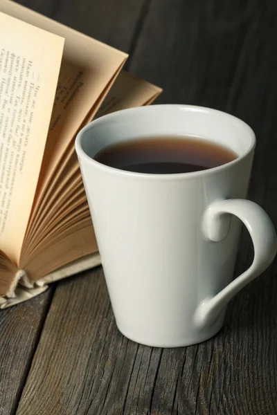 Tasse de thé avec vieux livre ouvert sur table en bois — Photo
