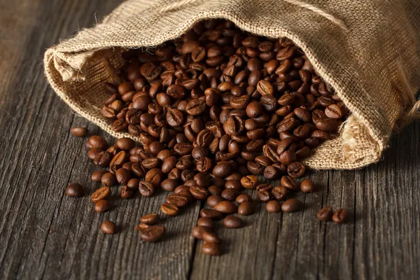 Bolsa de café con granos de café en superficie de madera —  Fotos de Stock