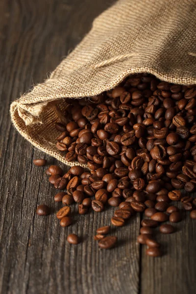 Coffee bag with coffee beans on wooden surface — Stock Photo, Image