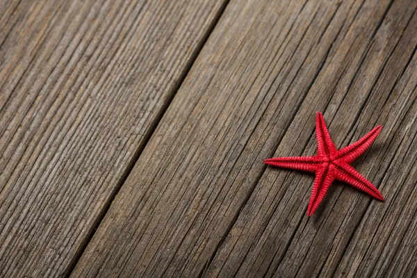 Red starfish seashell on old wooden surface. — Stock Photo, Image