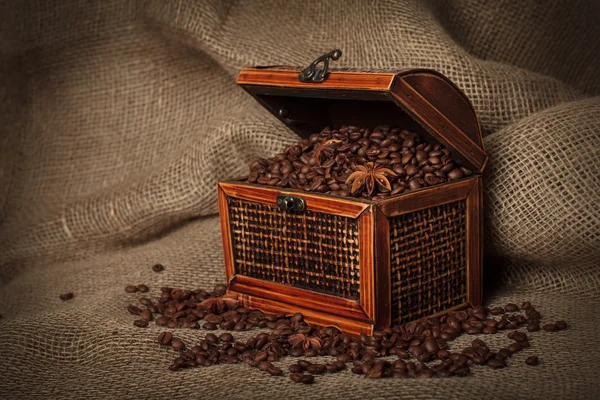 Old wooden treasure chest filled with coffee beans and anise stars . — Stock Photo, Image