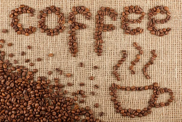 从咖啡豆在麻布的模式布局咖啡标题与杯. — 图库照片