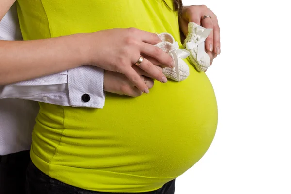 Una giovane donna incinta felice che tiene piccole scarpe per il nascituro — Foto Stock
