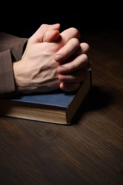 Ellerini dua kutsal İncil katlanmış.