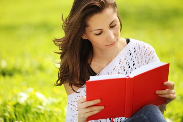 Изображение молодой красивой женщины в летнем парке, читающей книгу — стоковое фото