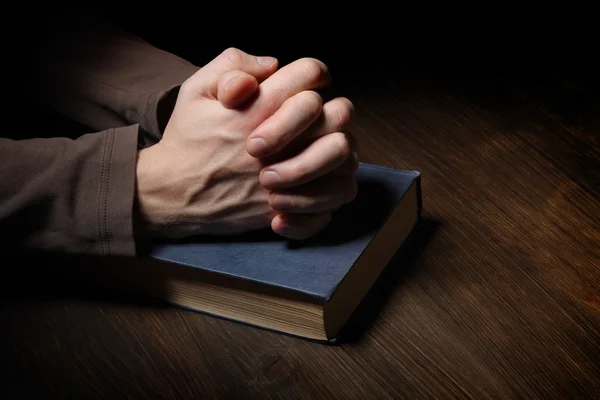 Hands folded in prayer over a Holy Bible — Stock Photo, Image