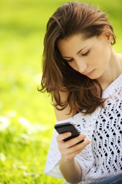 Bild einer jungen schönen Frau im Sommerpark, die eine Nachricht liest — Stockfoto