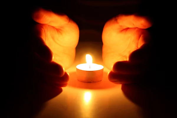 Mãos em volta de uma vela — Fotografia de Stock