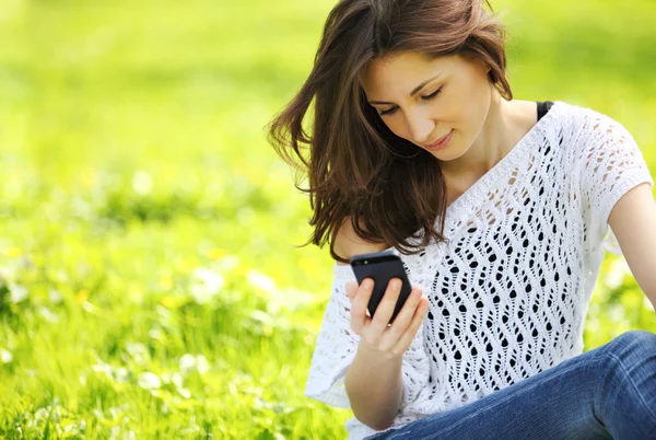 Bild einer jungen schönen Frau im Sommerpark, die eine Nachricht liest — Stockfoto