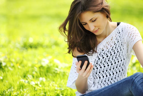 Bild einer jungen schönen Frau im Sommerpark, die eine Nachricht liest — Stockfoto