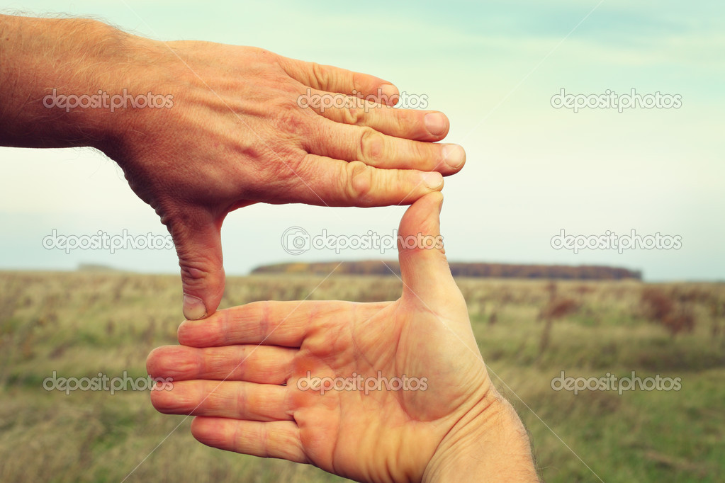 Image of two hands framing landscape composition