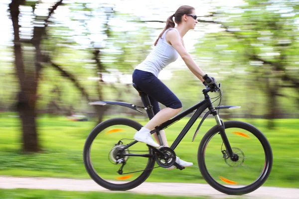 Pretty woman with bicycle in a green park — Stock Photo, Image