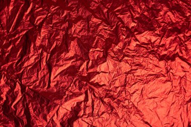 Kırmızı tonda, buruşmuş gümüş alüminyum folyo dokusunun yakın çekimi. Soyut arkaplan, tasarım için kullan