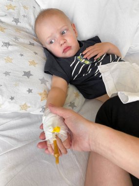 Mother holding childs hand who fever patients in hospital to give encouragement.