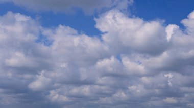 Güneşli bir yaz gününde mavi gökyüzü olan kümülüs bulutları. Doğa arkaplan manzarası olarak güzel bulutlar. Beyaz bulutların yüzdüğü, soyut bir şekil oluşturan doğal gün ışığının harika havası.