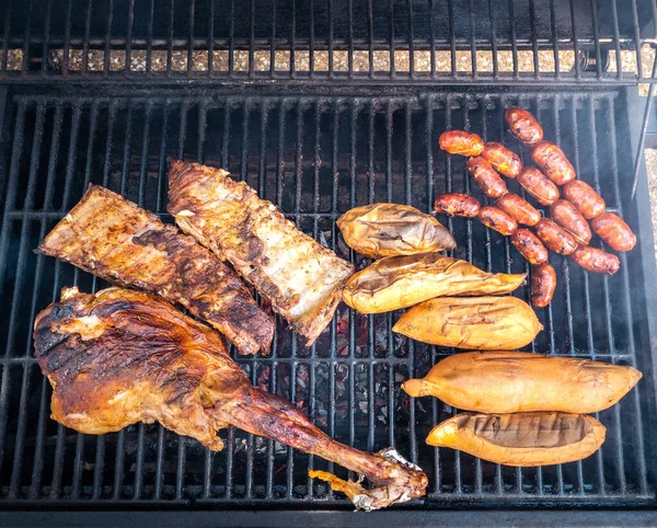 在烤好的金属盘子里烹调美味的羊腿和猪排 在烧烤架上煮一份什锦肉肠和红薯 主厨在房子的后院烹调猪肉 — 图库照片