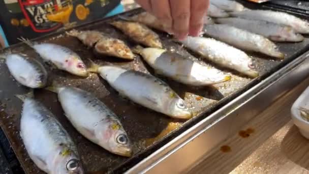 シェフは塩をグリルプレートの上にイワシのグリルに入れました 休日の休暇で庭の家で準備されたスペイン語のピチャードスタイルを閉じます 人は台所の外で魚を調理する 伝統的なシーフードスペイン — ストック動画